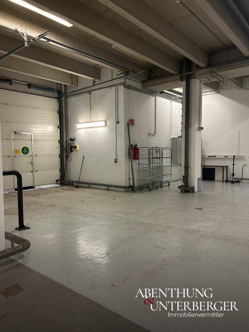Industriehalle mit großem Rolltor, Feuerlöscher und Metallwagen, bereit für den Betrieb.