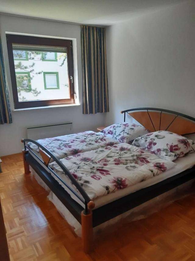 Schlafzimmer mit zwei Einzelbetten, Holzrahmen und Fenster mit Vorhängen, bietet viel Licht.