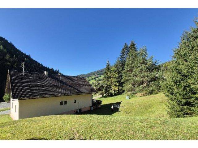 Rückansicht des Hauses mit großem Gartenbereich und Blick auf die Berge.
