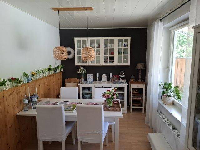 Esszimmer mit Holztisch, weißen Stühlen und dekorativer Wandgestaltung.