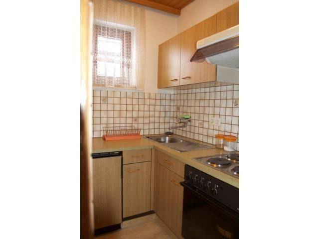 Kleine, funktionale Küche mit Holzschränken, Fliesenrückwand und Fenster.