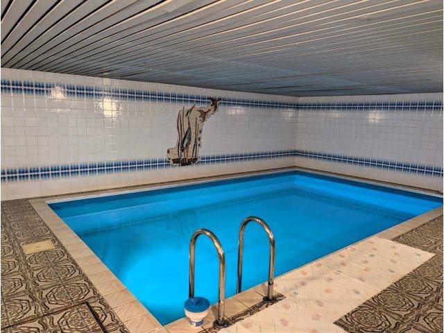 Innenpool mit blauen Fliesen und einem gemusterten Bodenbereich, ideal für Entspannung.