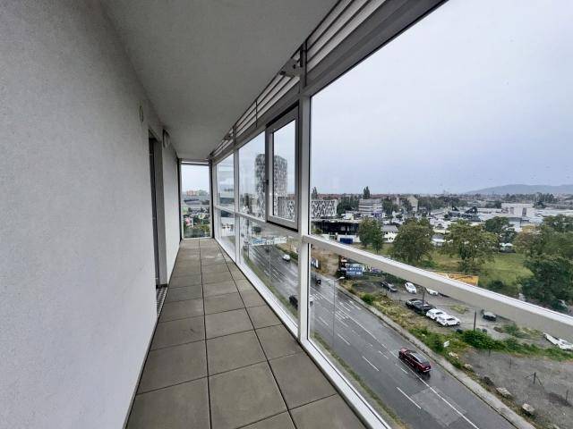 Langer Balkon mit Fliesenboden und Panoramablick auf die städtische Umgebung.