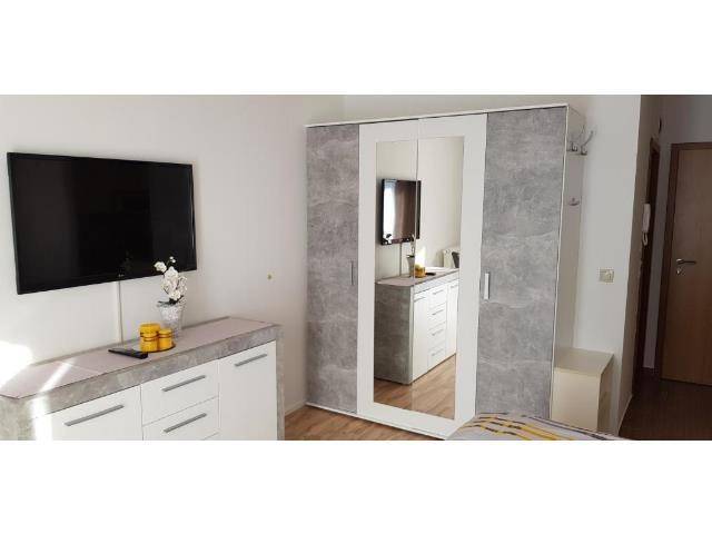 Modern eingerichtetes Schlafzimmer mit Wandfernseher und großem Spiegelschrank.