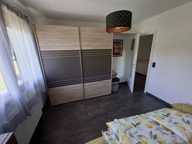 Schlafzimmer mit großem Schiebetürenschrank und dunklem Laminatboden.