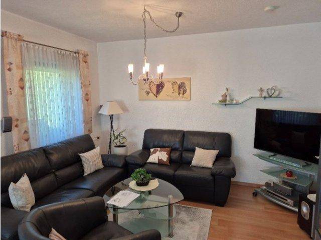 Wohnzimmer mit dunklen Ledersofas, Holzboden und einem Fernseher.