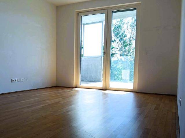 Heller Wohnraum mit Holzboden und großem Zugang zu einem Balkon.