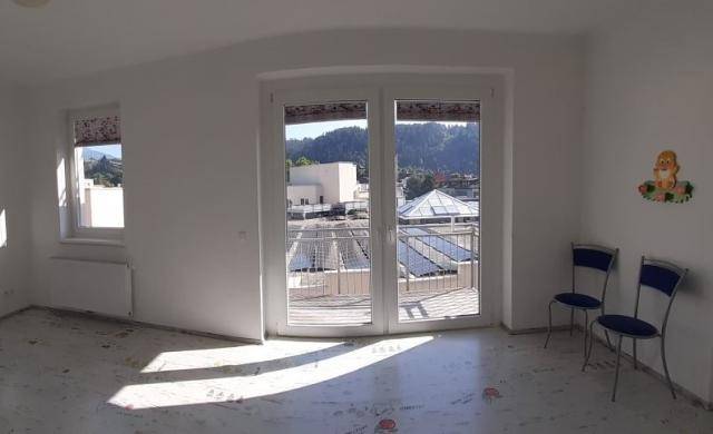 Heller, leerer Raum mit Zugang zu einem Balkon und Blick auf die umliegende Landschaft.
