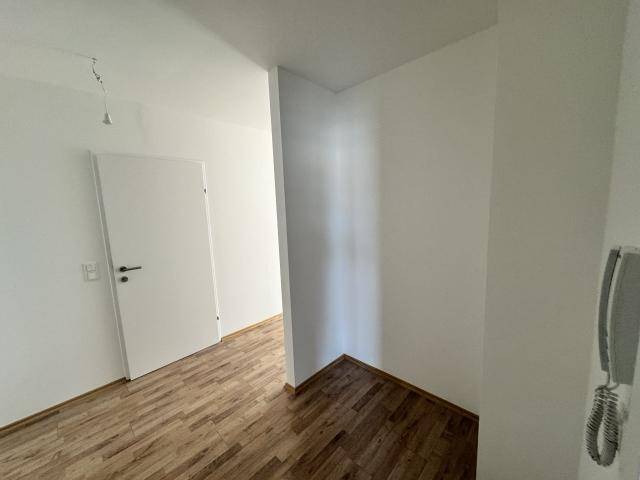 Heller Flur mit Holzboden und weiß gestrichenen Wänden, ausgestattet mit einer Gegensprechanlage.