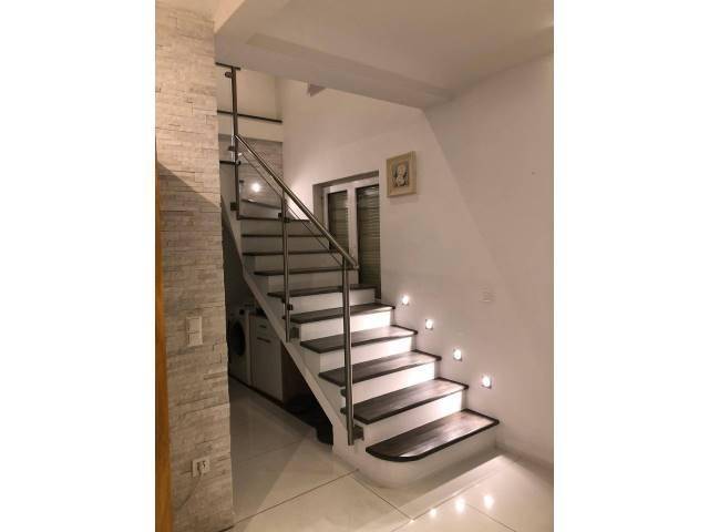 Moderne Treppe mit dunklen Stufen, Edelstahlgeländer und integrierter Wandbeleuchtung.