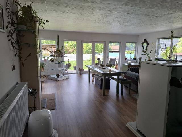 Heller Wohn- und Essbereich mit Laminatboden, großen Fenstern und direktem Zugang zum Garten.