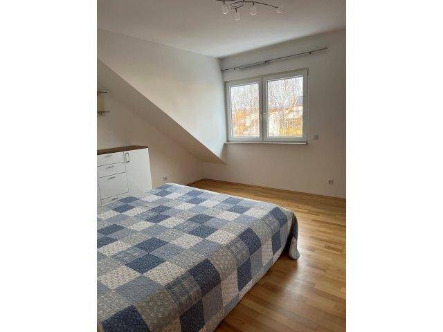 Helles Schlafzimmer mit Holzboden, Fenster und Blick ins Grüne.