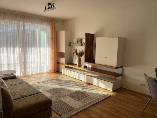 Helles Wohnzimmer mit beigem Sofa, Holzboden und Zugang zu einem Außenbereich.