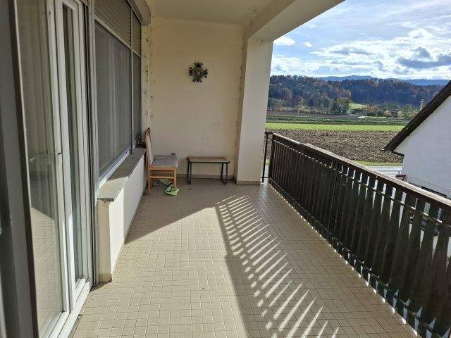 Geräumiger Balkon mit Fliesenboden und weitem Blick über Felder und Hügel.