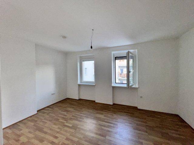 Geräumiger, heller Raum mit Holzboden und Fenstern, die einen Blick auf die Umgebung ermöglichen.