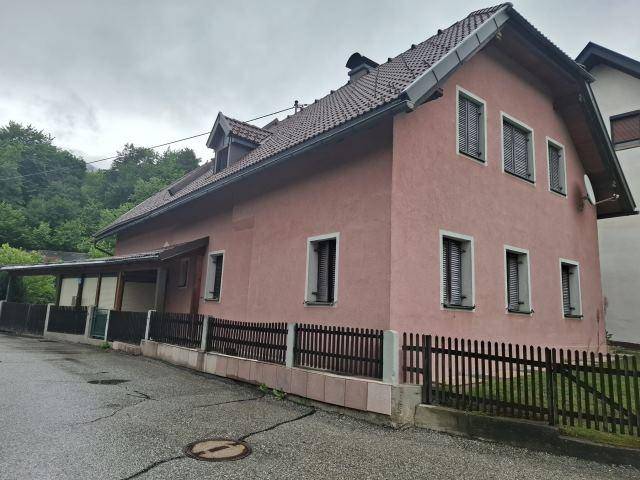 Einfamilienhaus mit rosafarbener Fassade, Ziegeldach und Fenstern mit Fensterläden.