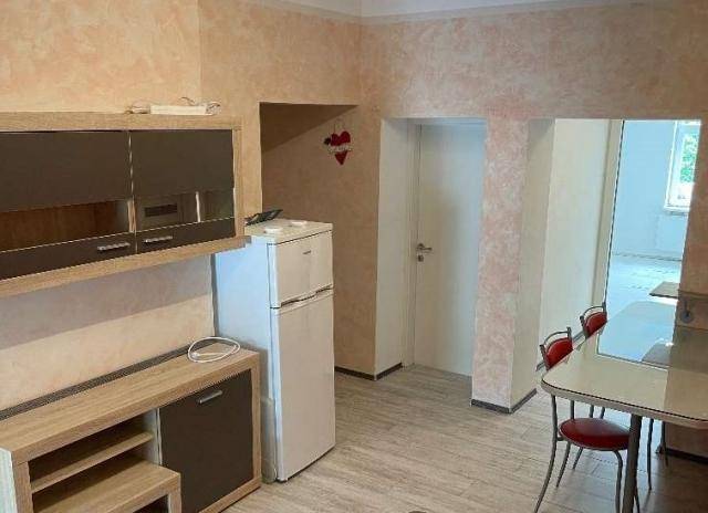 Kleine Küche mit Kühlschrank, Esstisch und strukturierten Wänden in warmen Farbtönen.