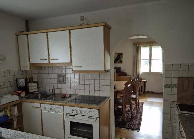 Rustikale Küche mit weißen Oberschränken, Fliesenspiegel und Durchgang zum Essbereich.