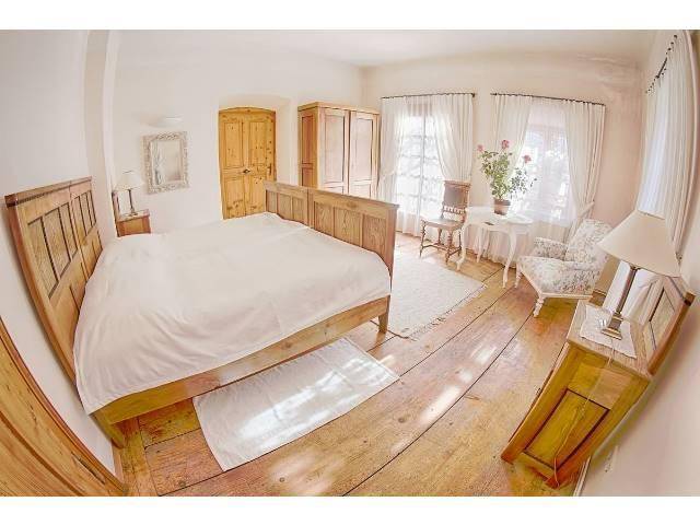 Helles Schlafzimmer mit rustikalem Holzbett, breiten Dielenböden und traditionellen Holzmöbeln.
