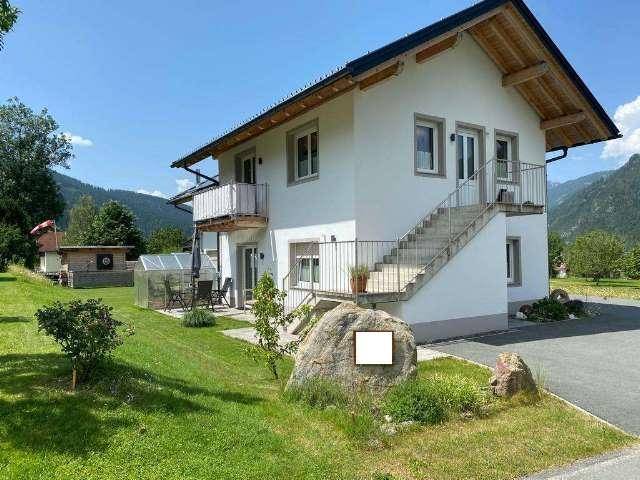 Rückansicht des Hauses mit Außentreppe, zwei Balkonen und weitem Bergblick.