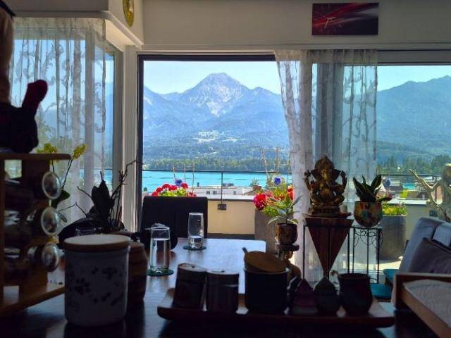 Heller Innenraum mit großen Fenstern bietet einen atemberaubenden Blick auf den See und die Berge.