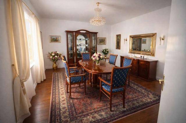 Geräumiges Esszimmer mit großem Holztisch, blauen Stühlen und einem eleganten Kronleuchter.