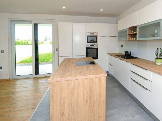 Helle, moderne Küche mit weißen Schränken, Holzinsel und Zugang zur Terrasse.