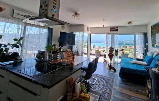 Offener Wohnbereich mit moderner Küche, Essbereich und Zugang zur Terrasse mit Seeblick.