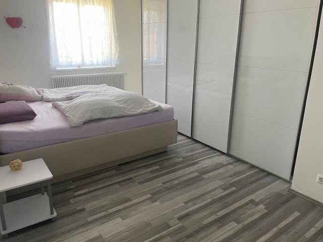 Gemütliches Schlafzimmer mit großem Bett, weißem Kleiderschrank und hellem Laminatboden.