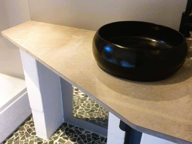 Detailansicht eines Badezimmers mit modernem Aufsatzwaschbecken und Mosaikboden.