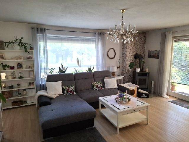 Helles Wohnzimmer mit großem Ecksofa, Holzboden und Zugang zur Terrasse.
