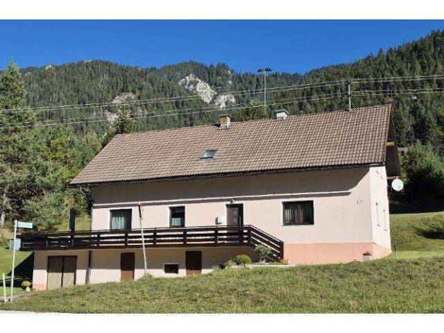 Einfamilienhaus mit Balkon und Satteldach in ländlicher Berglandschaft.
