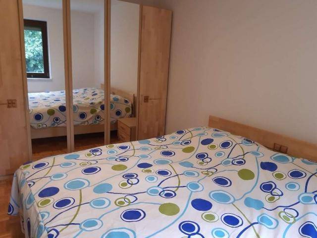 Schlafzimmer mit Doppelbett, Spiegelschränken und Fenster mit Blick ins Grüne, sehr hell.