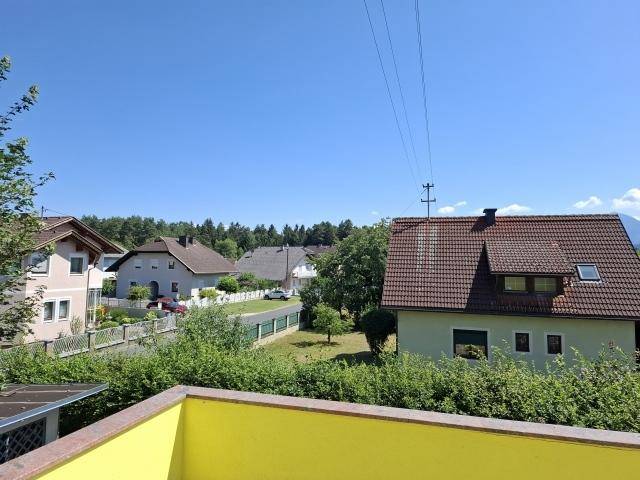 Weitblick über eine ruhige Wohnsiedlung mit Einfamilienhäusern und viel Grün unter blauem Himmel.