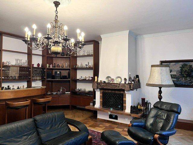 Gemütliches Wohnzimmer mit Kamin, dunklen Ledersofas und einer eingebauten Bar mit Regalen.