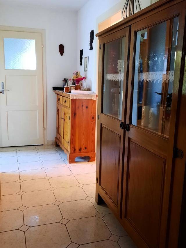 Heller Eingangsbereich mit traditionellen Holzmöbeln und gemusterten Fliesenboden.