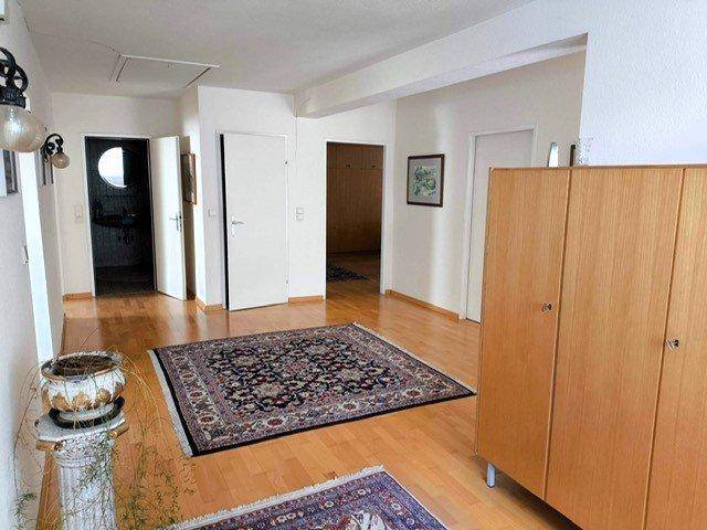 Heller Flur mit Holzfußboden, Teppich und mehreren Türen, die zu verschiedenen Räumen führen.