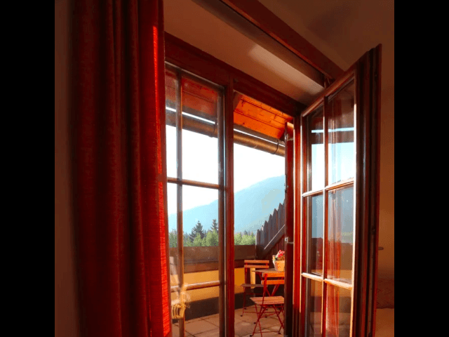 Heller Innenraum mit Zugang zum Balkon und Blick auf die Berge.