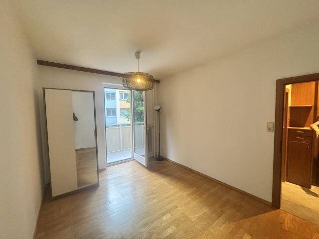 Helles Schlafzimmer mit Parkettboden, Kleiderschrank und Zugang zum Balkon.