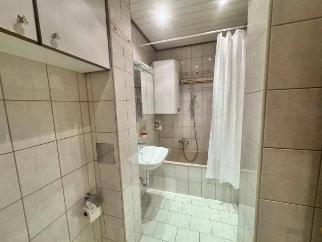 Gefliestes Badezimmer mit Badewanne, Dusche, Waschbecken und Spiegelschrank.