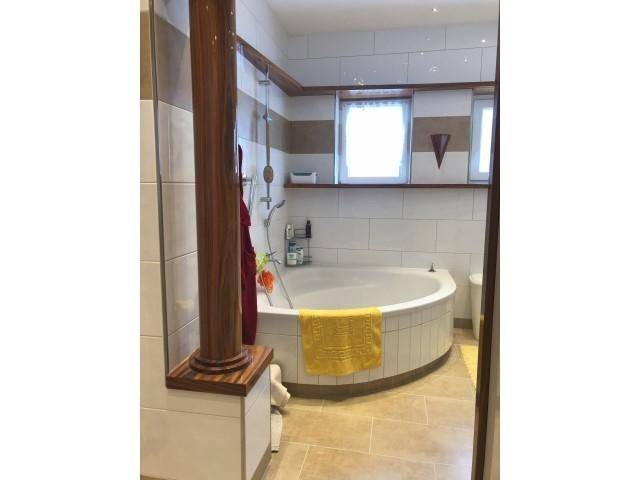 Badezimmer mit runder Badewanne, Duschbereich und hellen Fliesen.