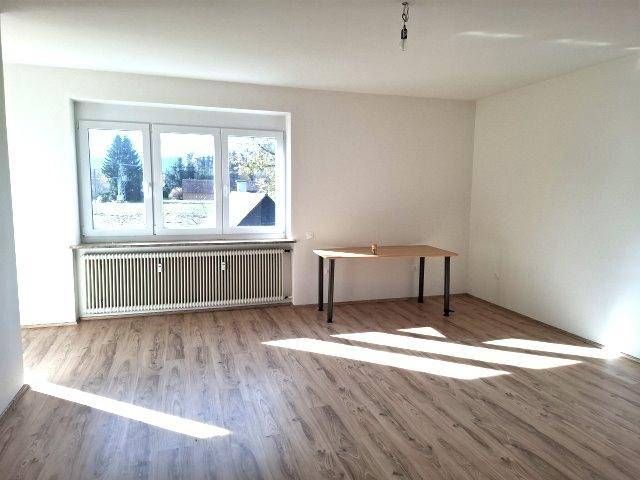 Geräumiger Raum mit Laminatboden, großen Fenstern und einem angenehmen Blick ins Grüne.