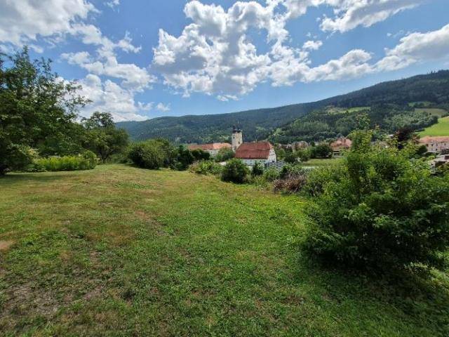 Weitläufiger Garten mit Rasenfläche und malerischem Blick auf ein Dorf und die Hügellandschaft.