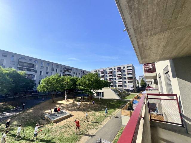 Helles, leeres Wohnzimmer mit Laminatboden und Zugang zu einem Balkon, der viel Tageslicht hereinlässt.