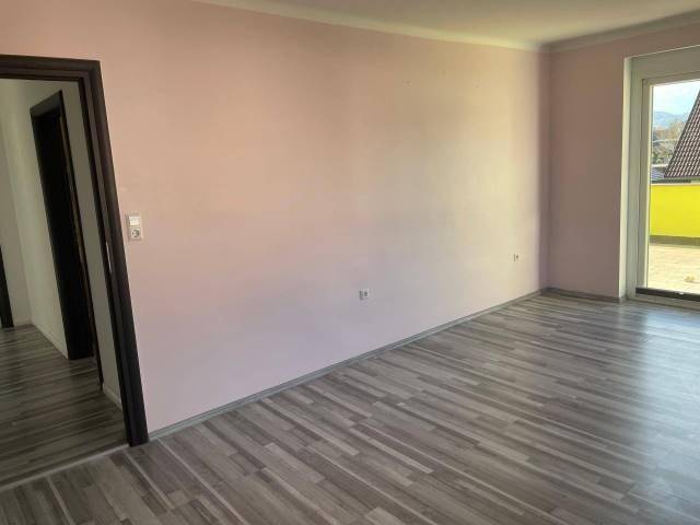 Leeres Zimmer mit hellrosa Wänden und modernem Laminatboden, ideal als Schlaf- oder Gästezimmer.
