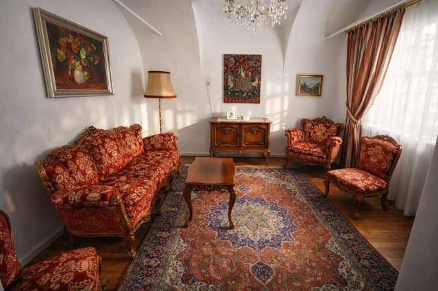 Traditionelles Wohnzimmer mit gewölbter Decke, opulenten Möbeln und einem großen Orientteppich.