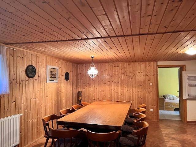 Rustikaler Essbereich mit Holztäfelung an Wänden und Decke sowie großem Holztisch.