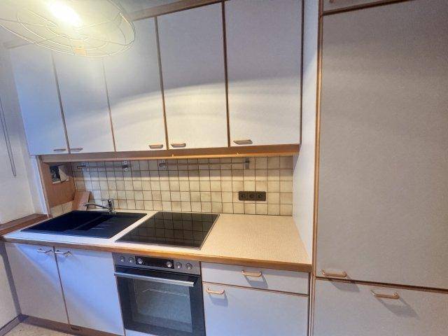 Funktionale Küche mit hellgrauen Schränken, Induktionskochfeld und gefliestem Spritzschutz.