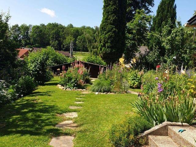Weitläufiger, gepflegter Garten mit Rasenfläche, Blumenbeeten und Gartenhaus.