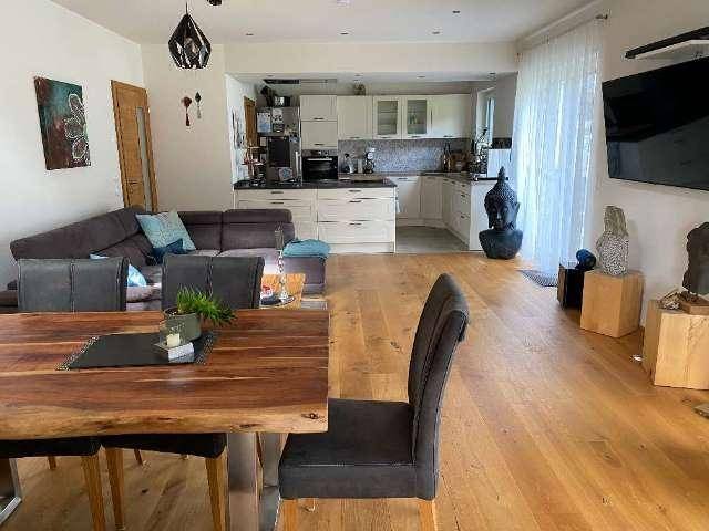 Offener Wohn- und Essbereich mit integrierter Küche und Holzboden.